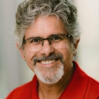 Jay Gupta wearing glasses, and a red shirt
